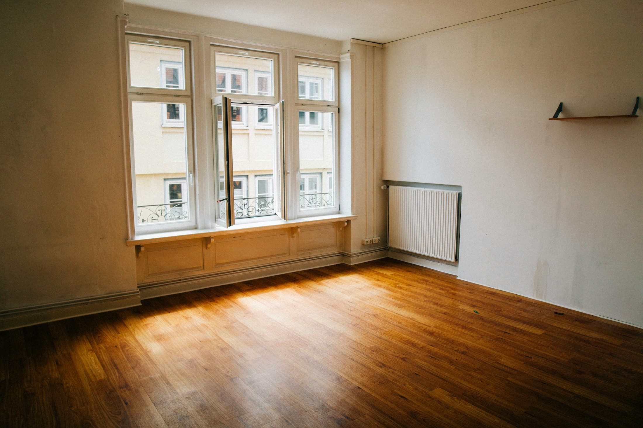 Leerer Raum mit Holzboden und großem Fenster im Tageslicht